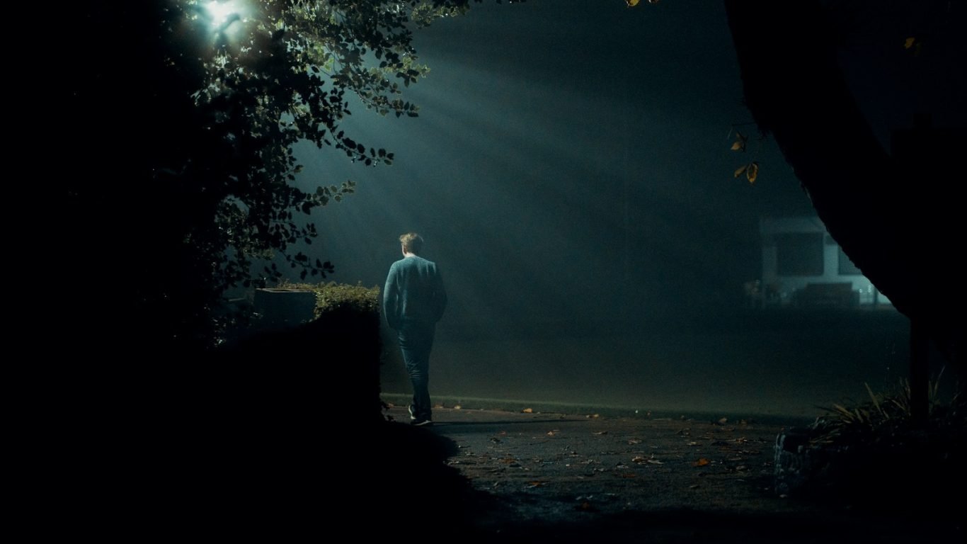a man standing in the dark under a street light
