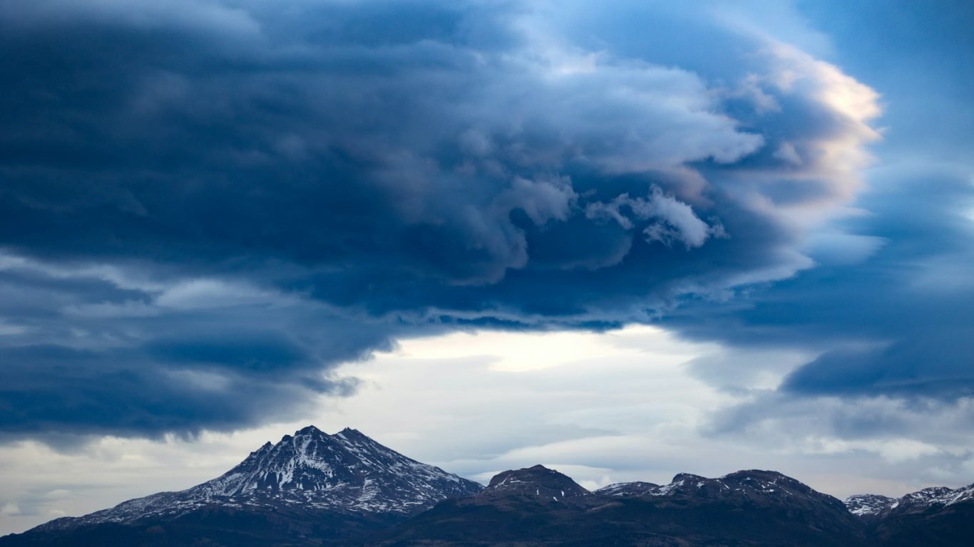 Dark clouds hover over snow-capped mountain peaks.